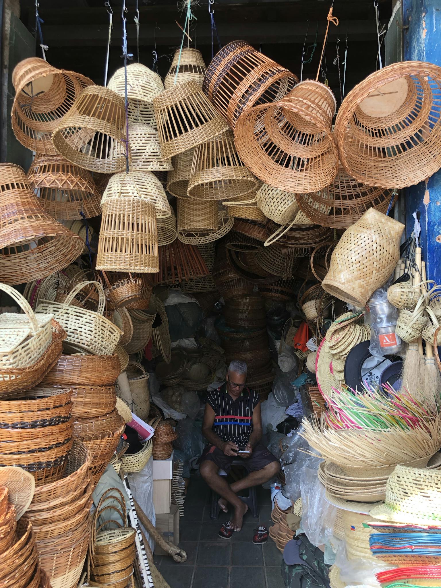 A vibrant display of handmade woven baskets in an artisanal shop with a seated vendor.