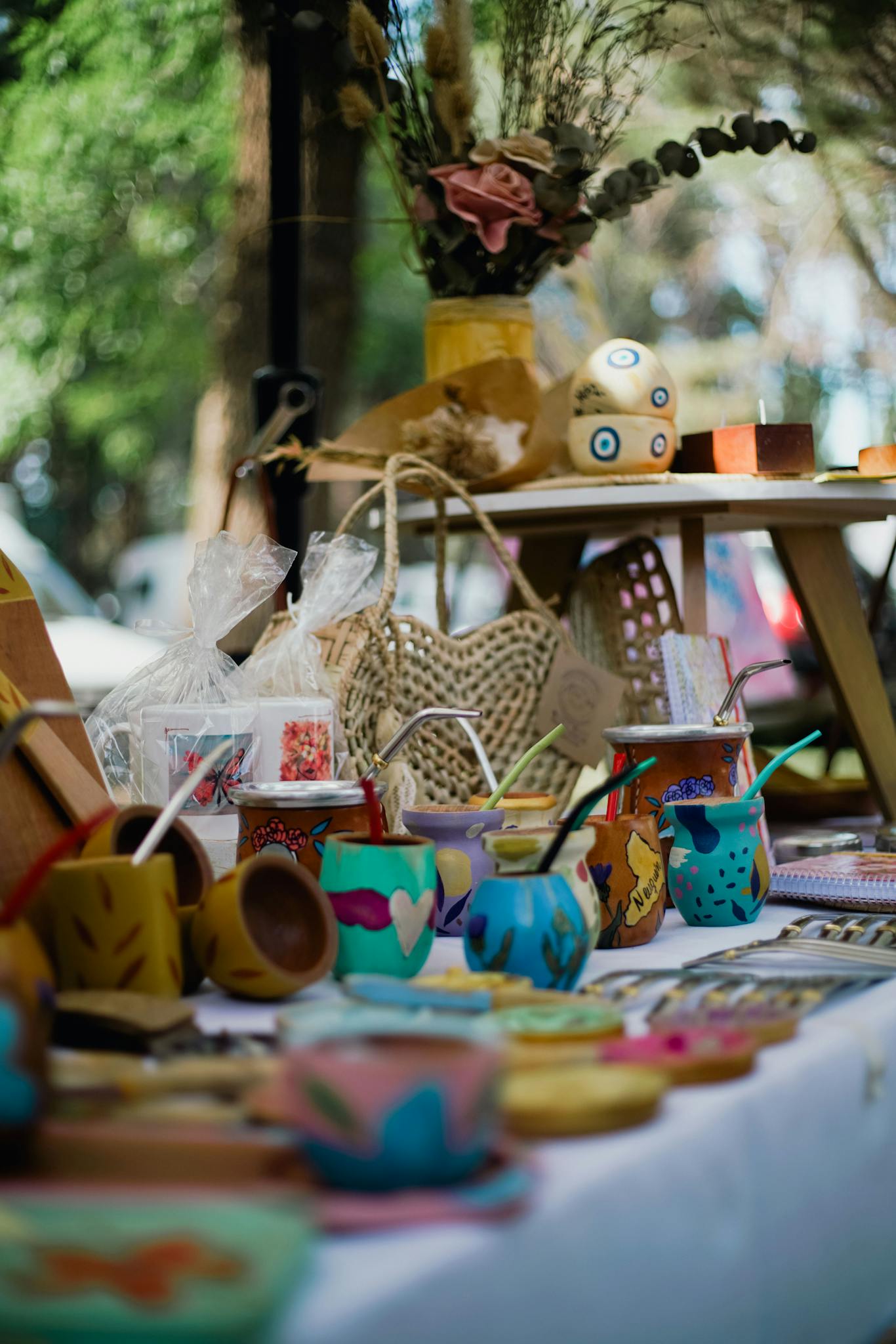 Vibrant outdoor market scene showcasing handmade cups, crafts, and decorations on a table.